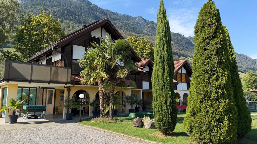 Weite Ansicht des Hauptgebäudes mit Palmen und hohen Koniferen